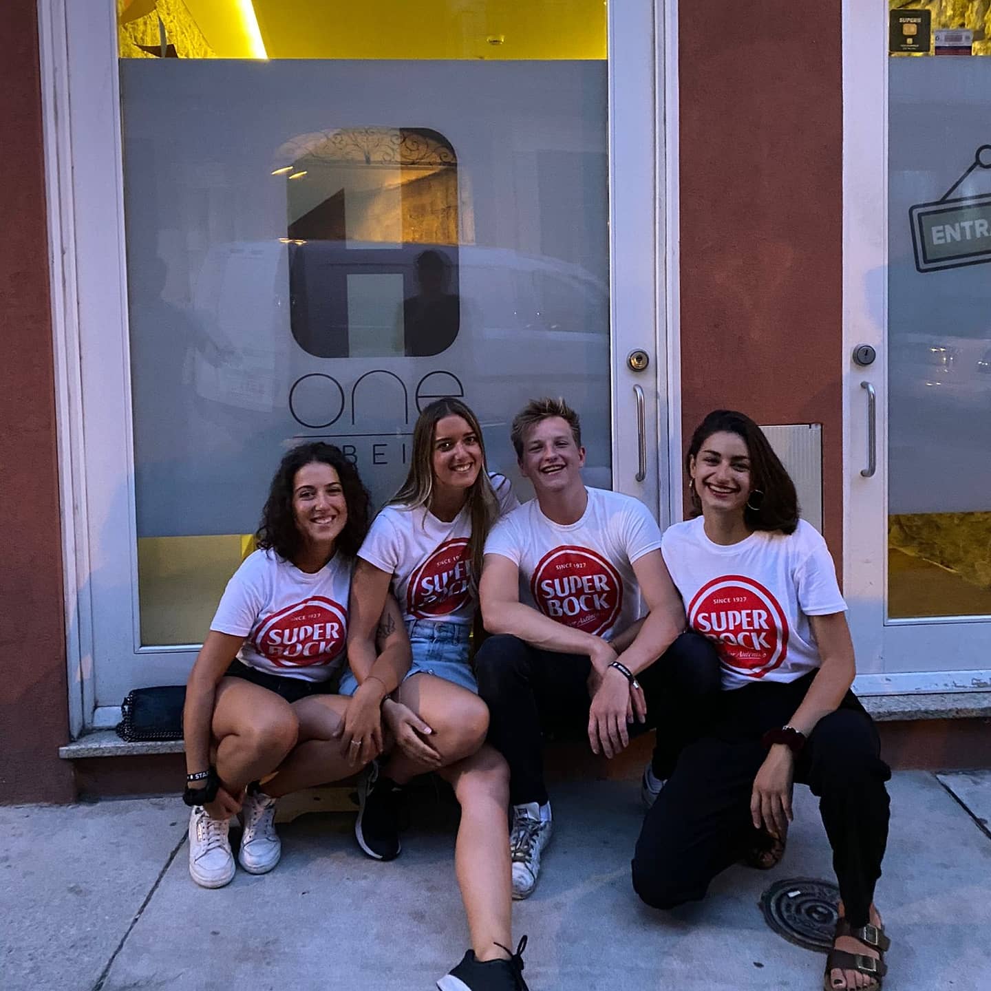 Four friends outside a hostel in Porto wearing Super Bock t-shirts